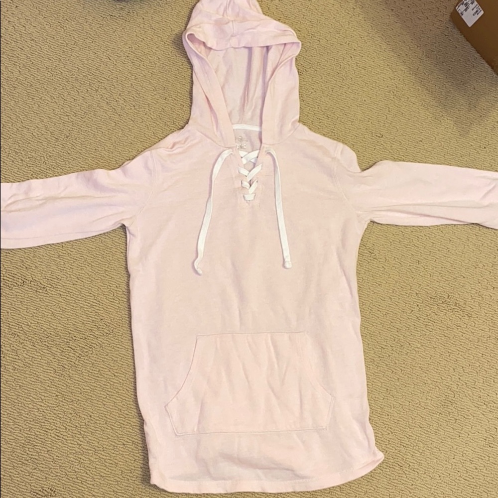 Pink hoodie with cross strings, pocket in front.